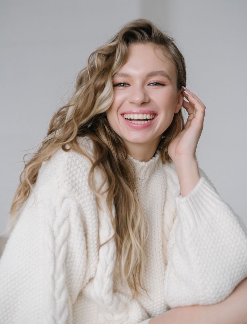 young woman in white sweater laughing