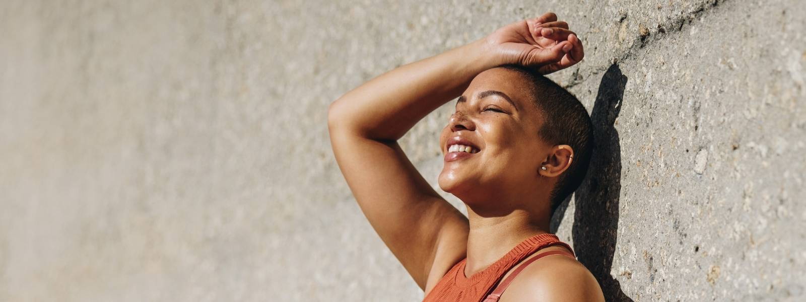 woman side profile smiling leaning against a wall
